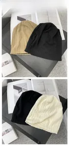 Flache Ansicht weicher Strickmützen in Beige, Schwarz und Weiß mit Wellenstruktur