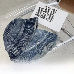 Detailed view of dark blue washed denim bucket hat with distressed frayed edges and texture