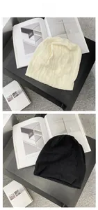 Detaillierte Nahaufnahme von dicken Strickmützen in Beige und Schwarz mit Wellenmuster