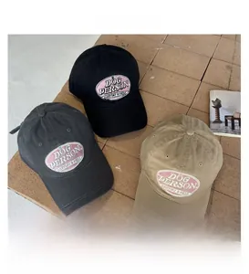 Detailed embroidery of retro DOG PERSON logo on cotton washed baseball caps in neutral tones
