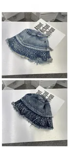 Detailed view of washed denim bucket hat with distressed frayed edges on metal surface
