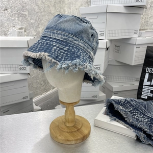 Retro washed denim bucket hat with distressed frayed edges on a wooden display stand