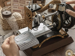 Close-up of vintage mini sewing machine model with retro fabric and decorative stickers