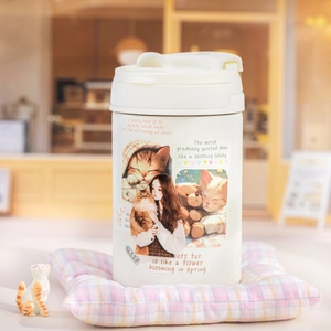 Insulated cat-themed coffee mug with cute kitty stickers on a cozy background
