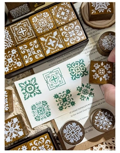Detail of vintage wooden stamps with green geometric floral ink patterns on white paper
