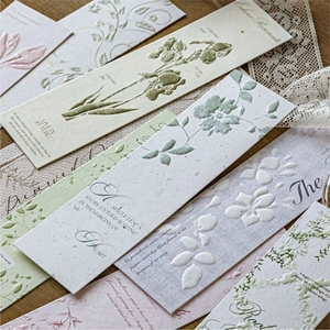 Floral embossed card bookmarks with iris and ivy patterns on dark wood background