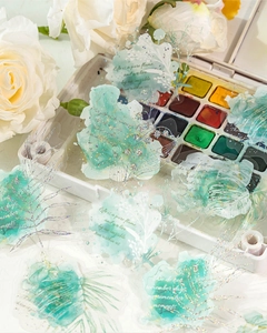 Detail of PET floral stickers with watercolor effect and glitter on a white palette background