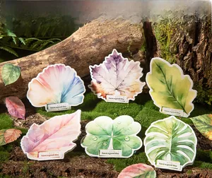 Detail view of 6 watercolor leaf stickers arranged on natural mossy bark for DIY journaling