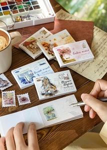 Detail of vintage watercolor stamp stickers on a rustic wood desk with stationery items