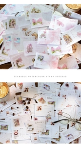 Detail of vintage stamp-style paper pads featuring watercolor cherry blossoms and cafes