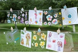 Close-up of floral girl stickers hanging with wooden clips in a sunny outdoor garden scene