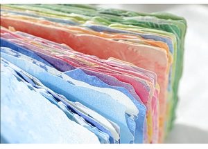 Detalle macro de papel artesanal texturizado arcoíris con bordes ondulados para manualidades