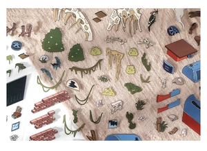 Detailed flat lay of dinosaur fossil and botanical DIY scrapbook stickers on brown fabric