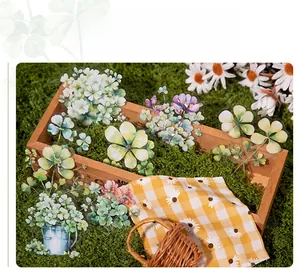 Close-up of holographic clover and floral PET stickers on a green moss box background