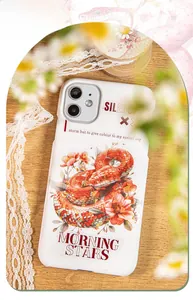 DIY floral snake stickers on a white iPhone case placed on a rustic wooden table surface