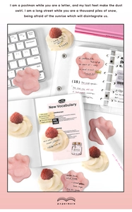 Close-up of pink cat paw sticky notes and strawberry dessert stickers on a notebook