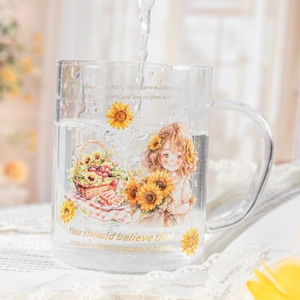 Glass sunflower mug with girl illustration and gold quotes in a cozy garden setting