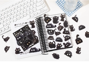 Vista detallada de lindos adhesivos de gato negro y papelería troquelada en un cuaderno