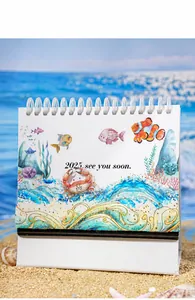 Close-up of 2025 ocean theme calendar with gold foil waves on a sunny beach background
