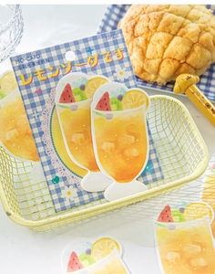 Detailed close-up of lemon soda watercolor sticky notes in a yellow wire basket
