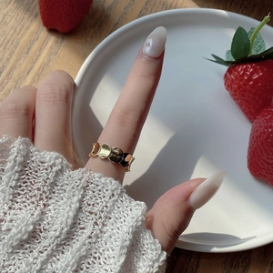 Close-up of golden scale-patterned ring worn on finger with minimalist design
