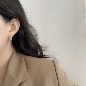 Elegant gold chain-textured hoop earrings worn by a model in a minimalist style