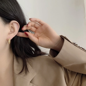 Detailed view of gold twist chain hoop earrings worn on a model for a stylish look