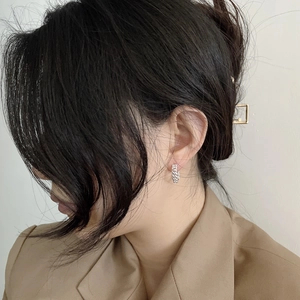 Close-up of S925 sterling silver chain hoop earrings worn by a model in brown suit