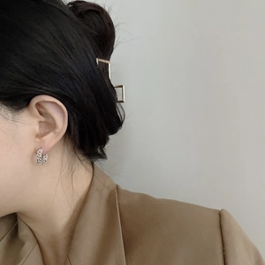 Close-up of S925 sterling silver chain link hoop earring worn by a model in beige blazer
