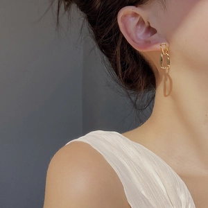 Detail of gold geometric irregular link earrings showing textured surface and metallic luster