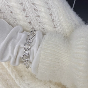 Close-up of polished S925 sterling silver chain bracelet on white textured sleeve
