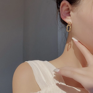 Detailed view of elegant gold-plated irregular chain earrings on a female model