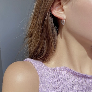 Detail of twisted 925 sterling silver U-shaped hoop earrings worn by a model