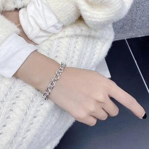 Detailed view of S925 sterling silver chain bracelet on a white knit sweater background