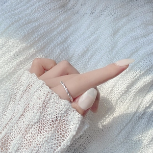 Detail of minimalist S925 sterling silver ring with textured surface worn on index finger