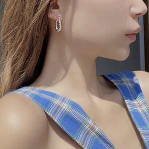 Détail de créoles torsadées en argent sterling S925 portées pour un style élégant
