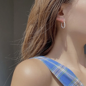 Créoles minimalistes en argent sterling S925 torsadées portées par un mannequin en lumière