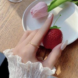 Detailed close-up of a slim golden woven texture ring worn on a woman's index finger