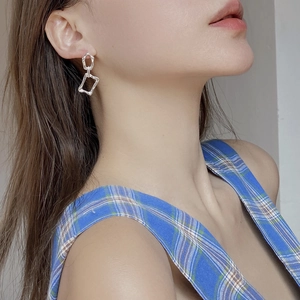 Detail shot of irregular geometric silver drop earrings worn on ear with casual styling