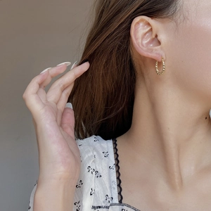 Gros plan de boucles d'oreilles créoles torsadées dorées avec texture vintage
