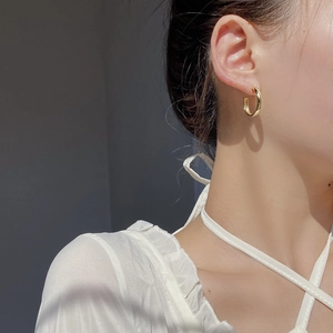 Élégantes boucles d'oreilles créoles C en argent s925 portées par un mannequin chic