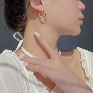 Gros plan d'une boucle d'oreille dorée en forme de C avec finition polie sur l'oreille