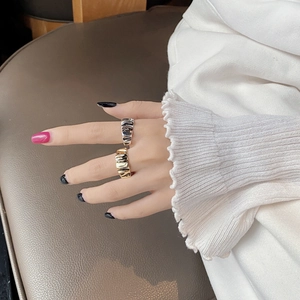 Detailed view of silver and gold irregular pleated texture open rings on hand