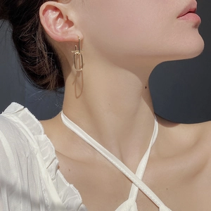 Close-up of minimalist gold geometric dangle earrings worn on a model's ear