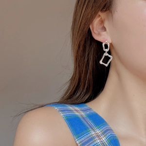 Irregular geometric silver earrings with chain link drop design worn by a model