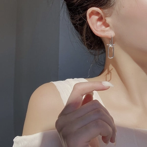 Close-up of geometric 925 silver earrings worn by a model with elegant shadows