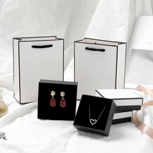 Elegant white jewelry box set with black trim featuring red teardrop earrings and necklace
