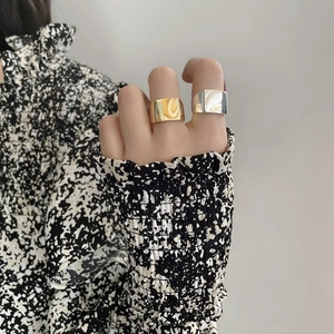 Detailed view of minimalist wide band rings in polished gold and silver finishes