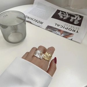 Detail of irregular textured S925 silver and gold rings with lava-like crushed metal design