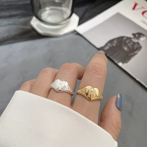 Macro detail of retro heart-shaped rings with engraved R letter and floral patterns